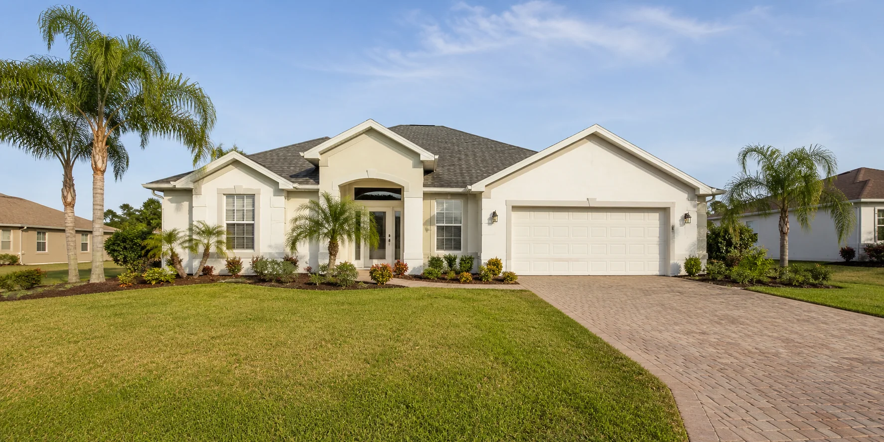 Well-maintained Cape Coral home with tropical landscaping and a paver driveway.