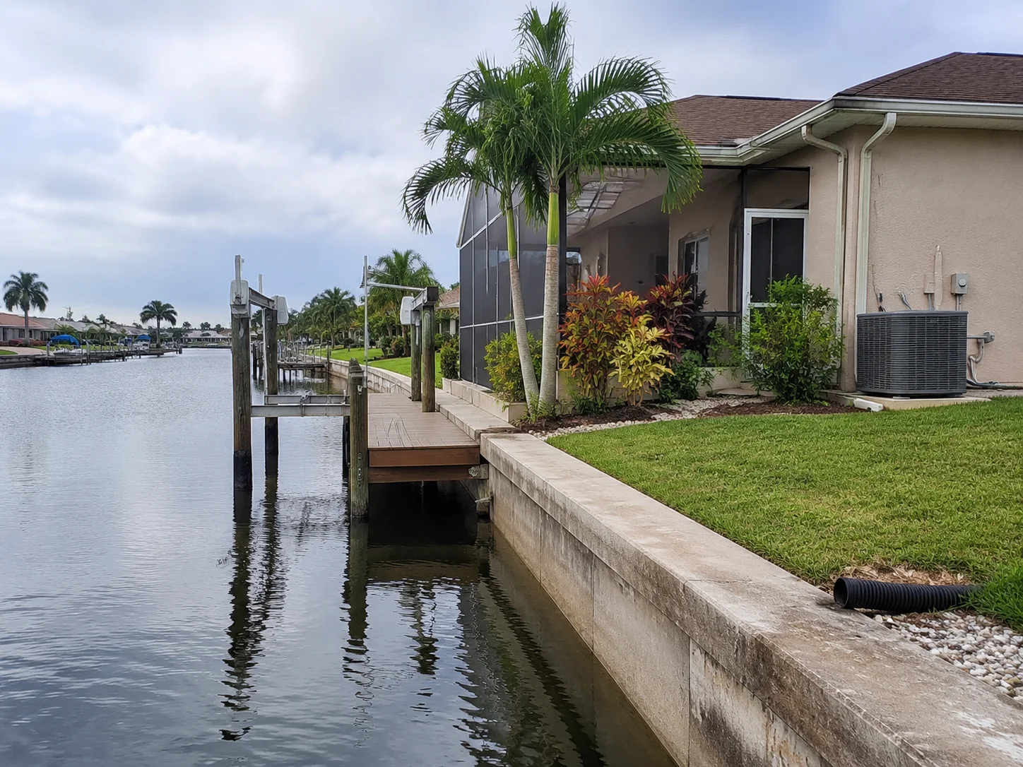 Cape Coral waterfront property with a seawall, dock, screened lanai and exterior air-conditioning system.