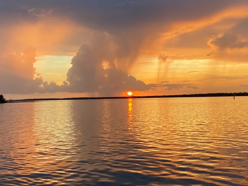 Golden sunset over open water beneath dramatic rain clouds