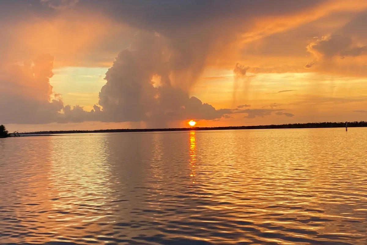 Golden sunset over open water beneath dramatic rain clouds