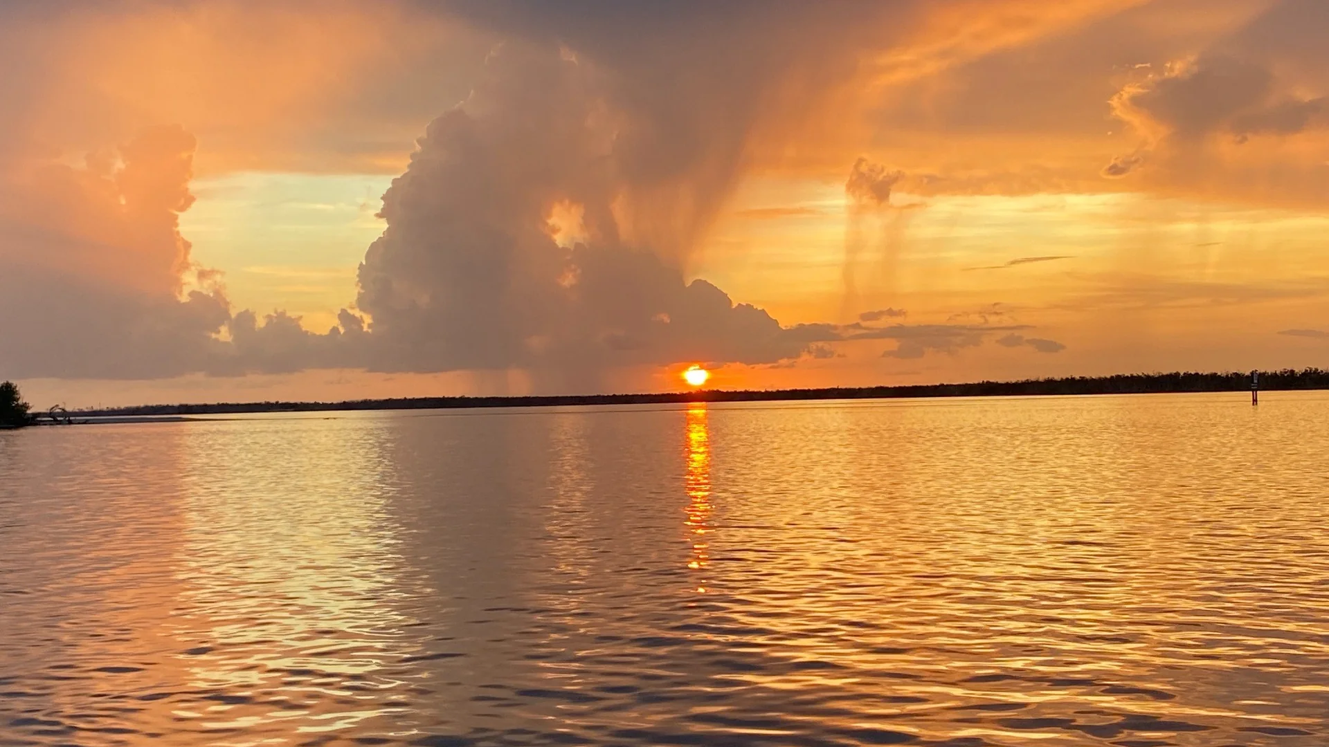 Golden sunset over open water beneath dramatic rain clouds, Southwest Florida