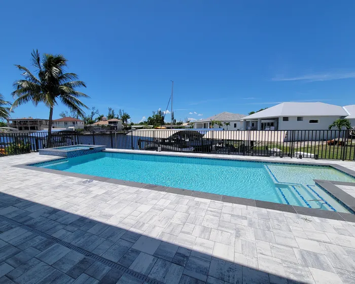 Screened pool with a canal dock in the background at a Cape Coral home
