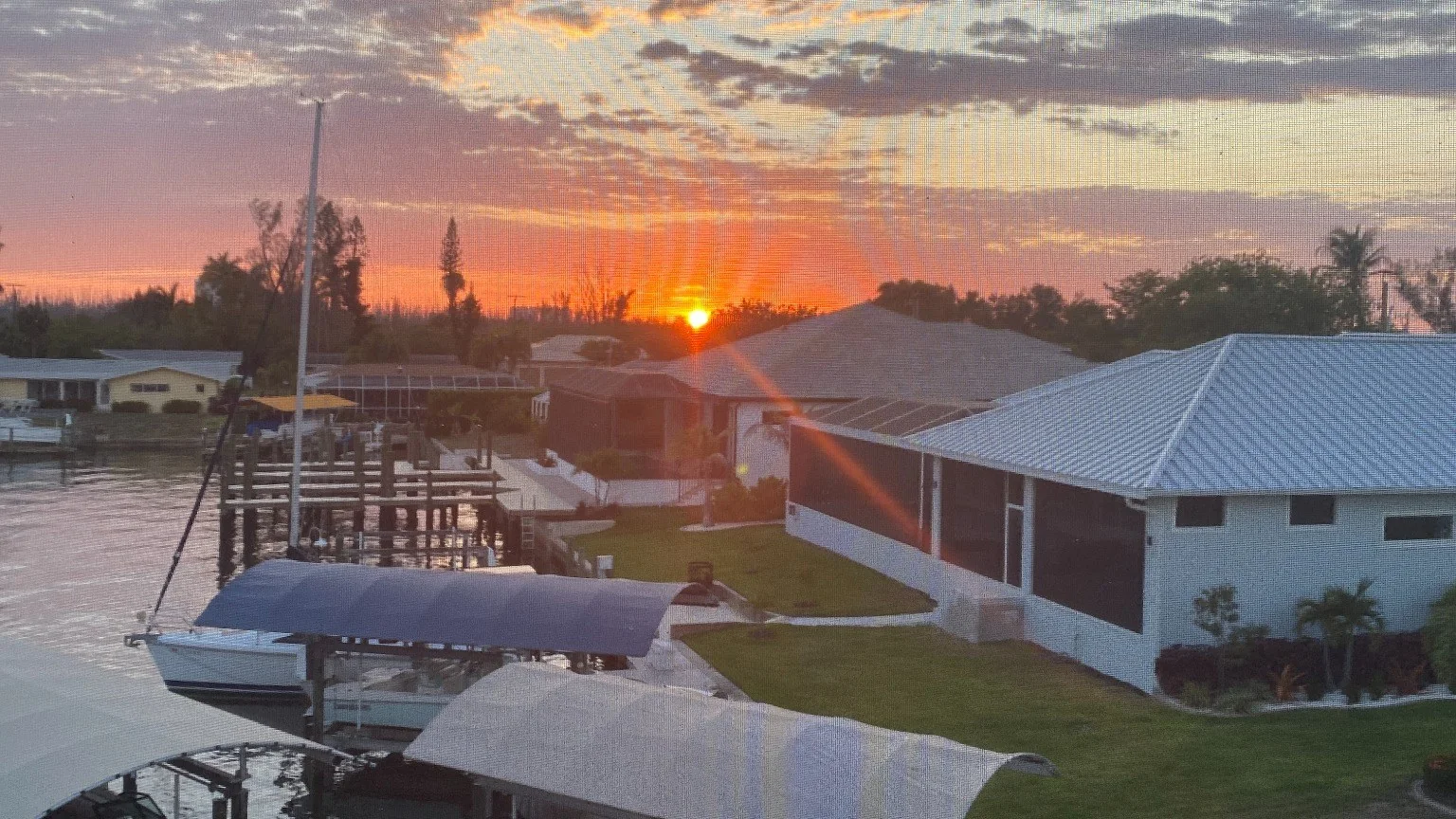 Sunset over a residential Cape Coral canal with docks, boats, and waterfront homes