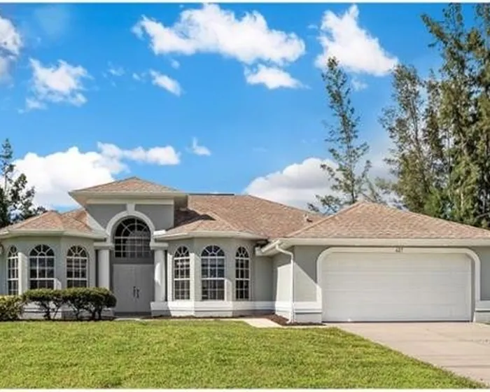 Single-family home on a Cape Coral street lined with mature landscaping