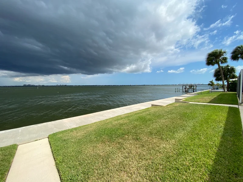 Storm clouds approaching a Southwest Florida riverfront property with a seawall and dock