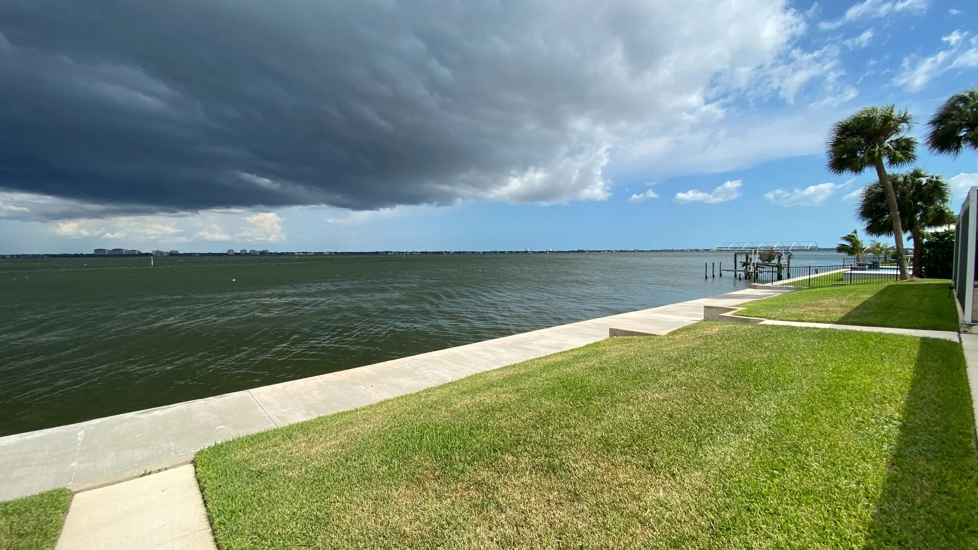 Storm clouds approaching a Southwest Florida riverfront property with a seawall and dock