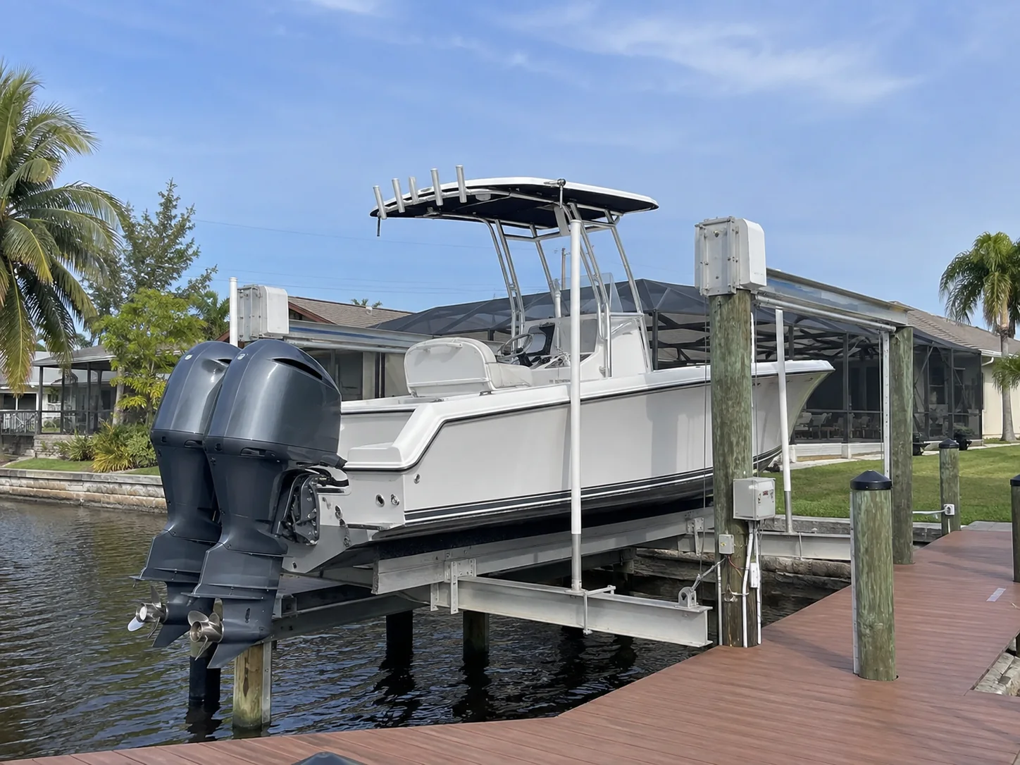 Center-console boat positioned on a residential Cape Coral boat lift with visible clearance and dock access.